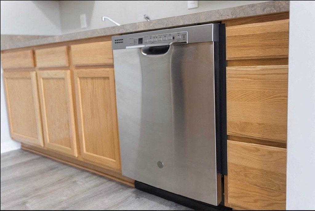 a stainless steel dishwasher in a kitchen with wooden cabinets