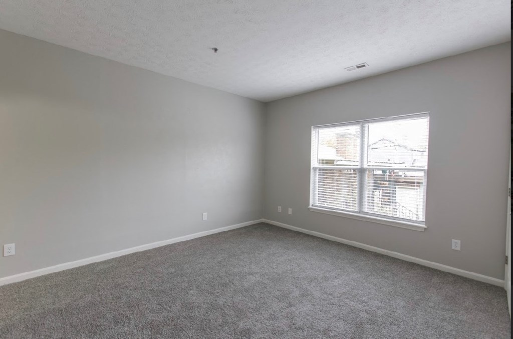 an empty living room with a window and carpet
