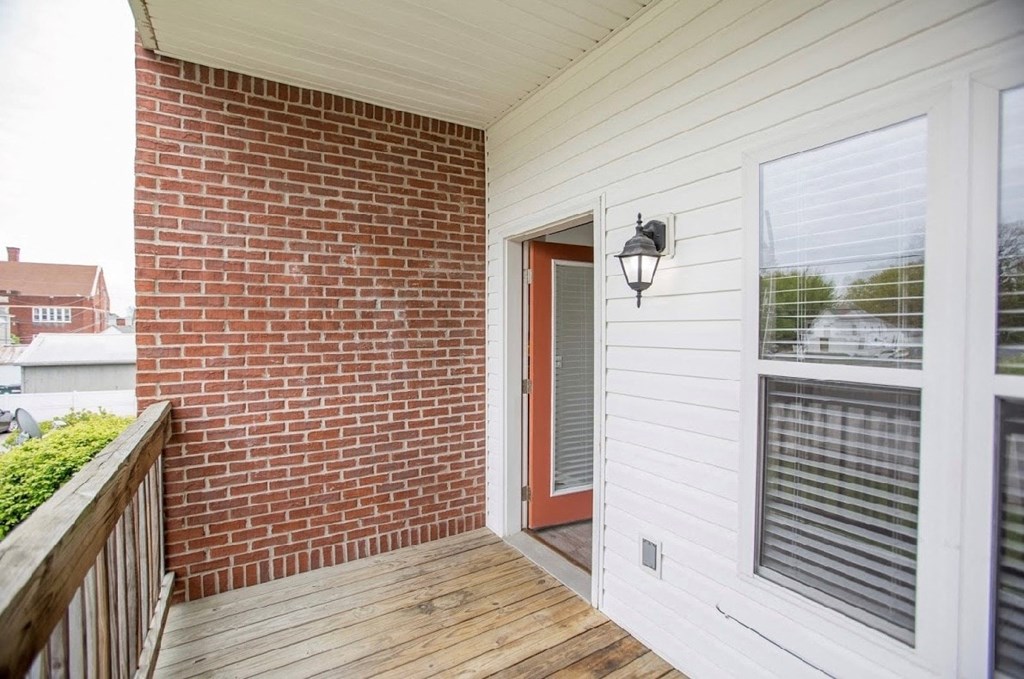 the front porch of a brick house with a red door