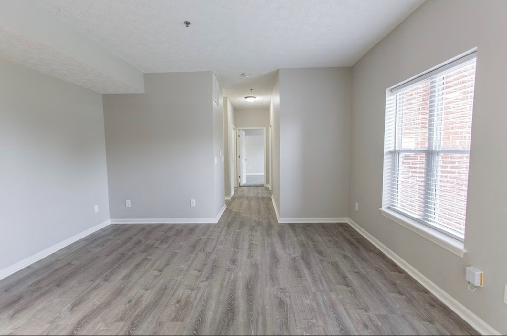 an empty living room with wood flooring and a large window