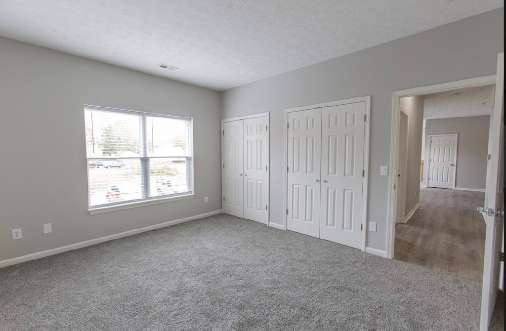an empty bedroom with two doors and a window