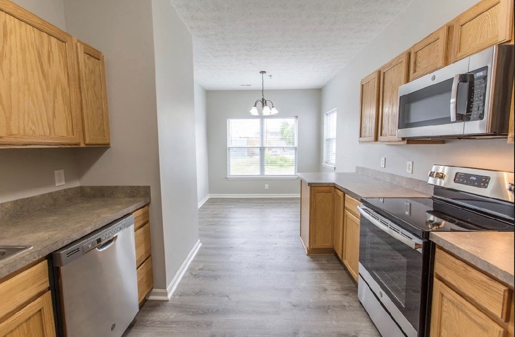 an empty kitchen with wooden cabinets and stainless steel appliances