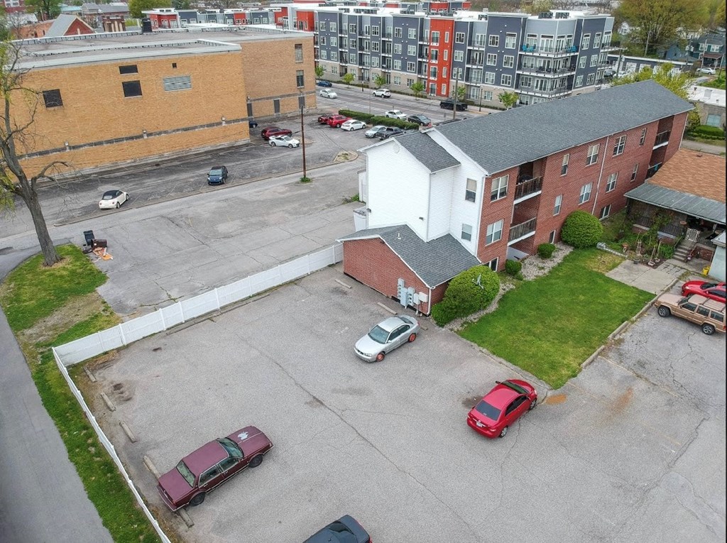 an aerial view of a parking lot with cars in front of a building