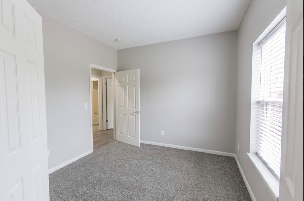 a bedroom with a door to a hallway and a carpeted floor