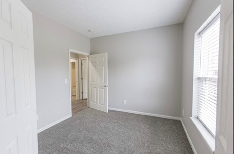 a bedroom with a door to a hallway and a carpeted floor