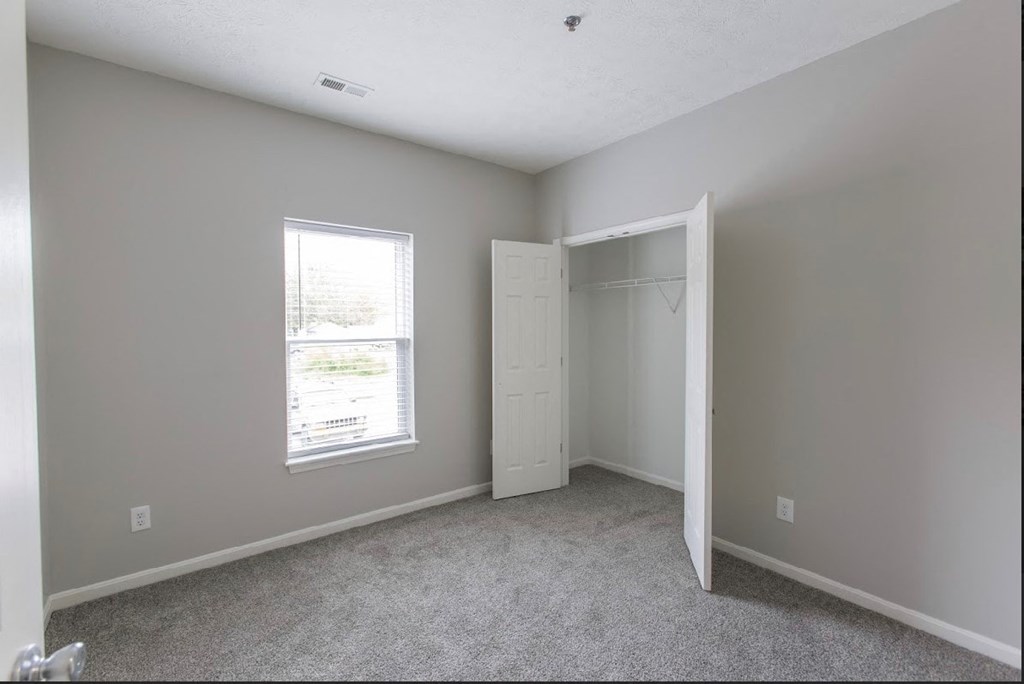 an empty bedroom with a closet and a window