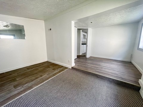 an empty living room with wood flooring and white walls