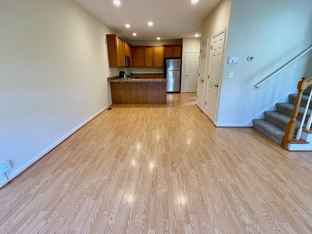 A kitchen with wooden floors and a staircase.