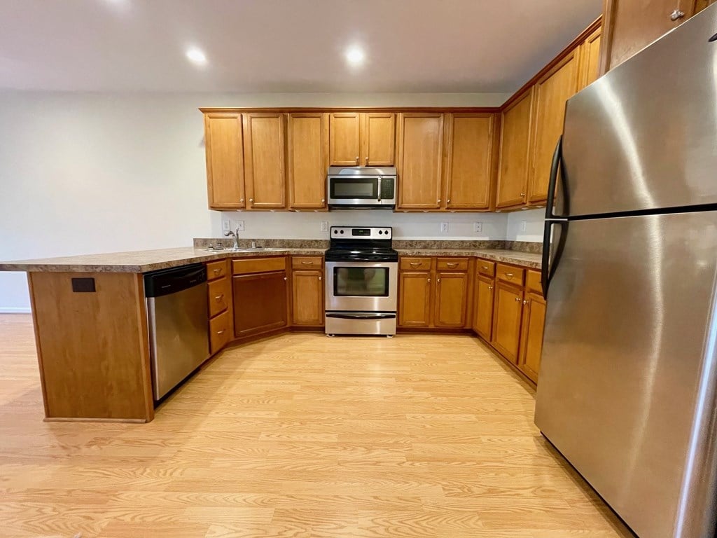 A kitchen with wooden cabinets and a stainless steel refrigerator.