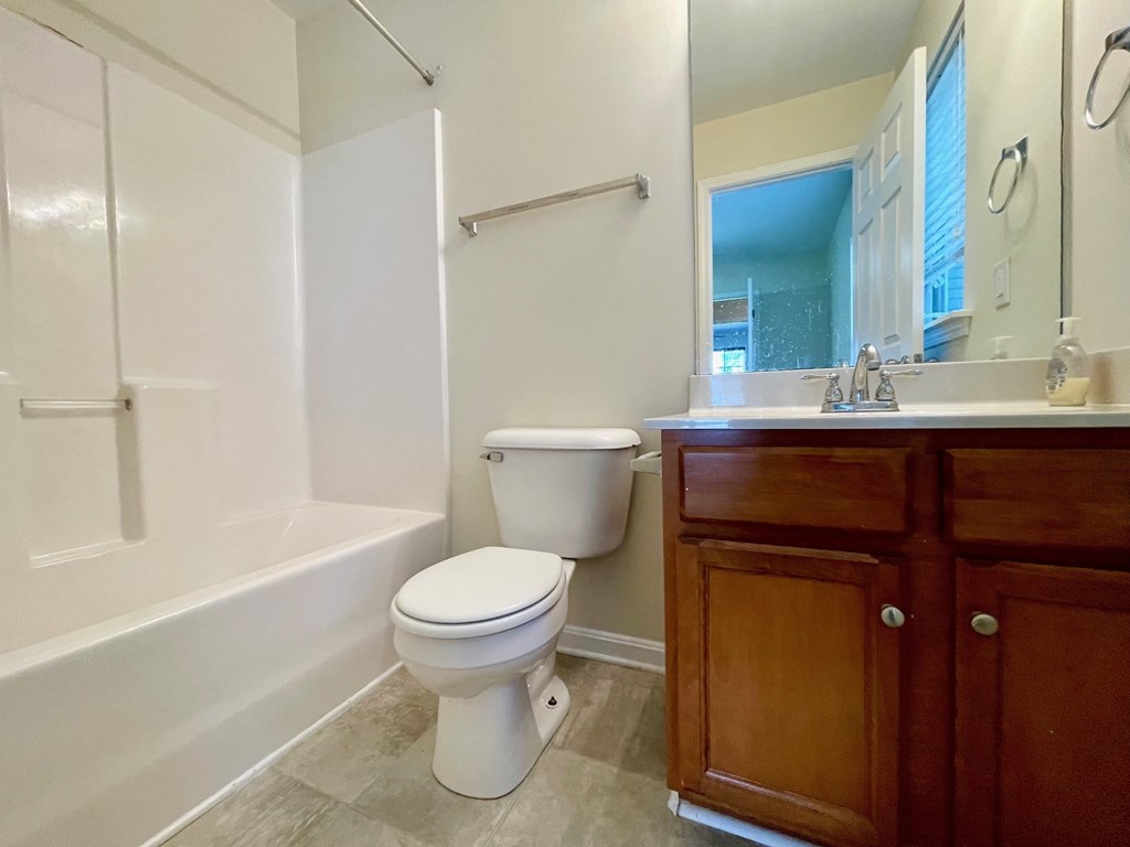 A white toilet sits next to a bathtub in a bathroom.