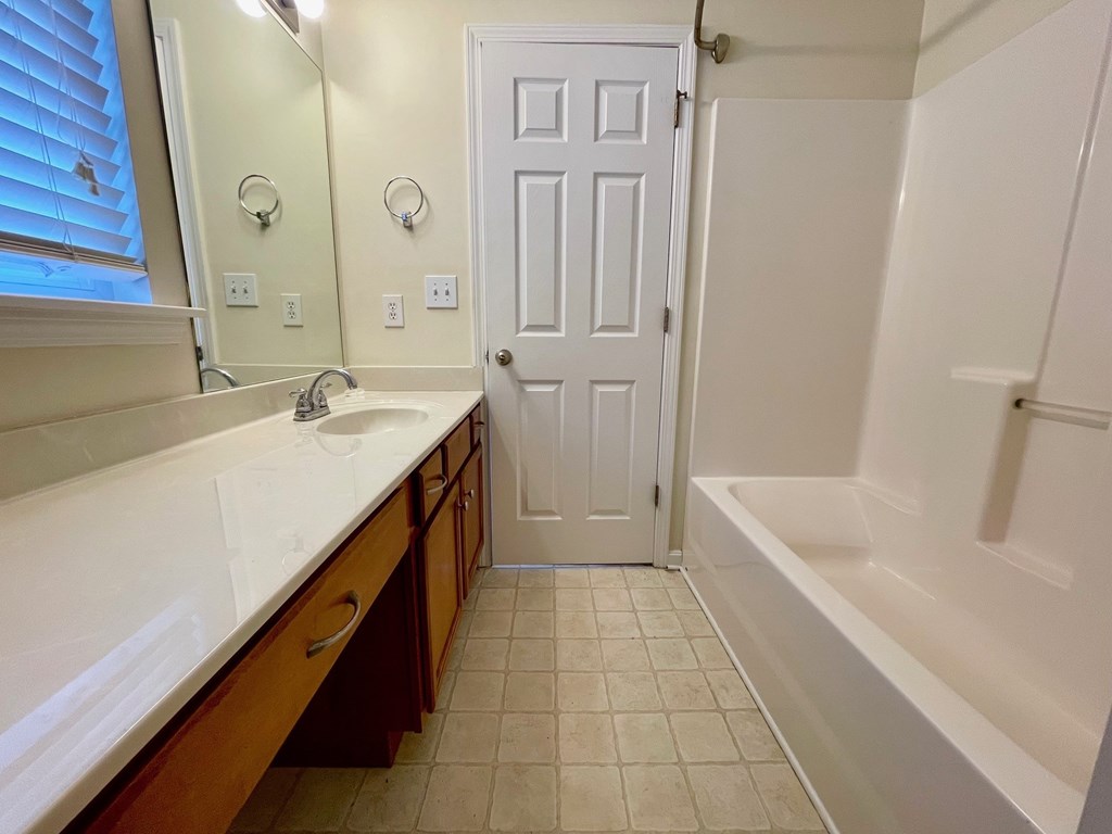 A white door is in a bathroom with a white tub and sink.