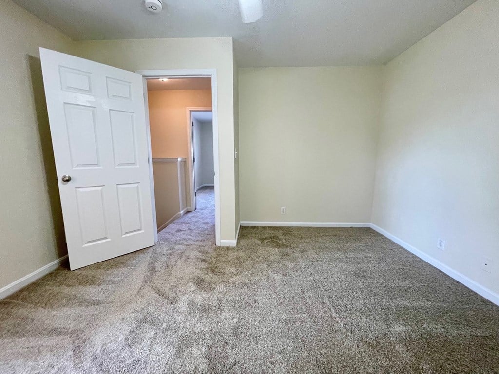 A room with a carpeted floor and a white door.
