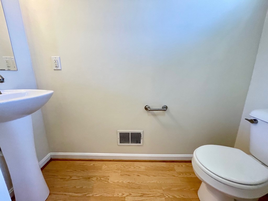 A white toilet in a bathroom with a wooden floor.