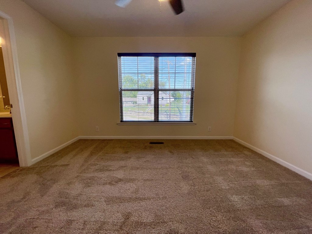 A room with a carpeted floor and a window.