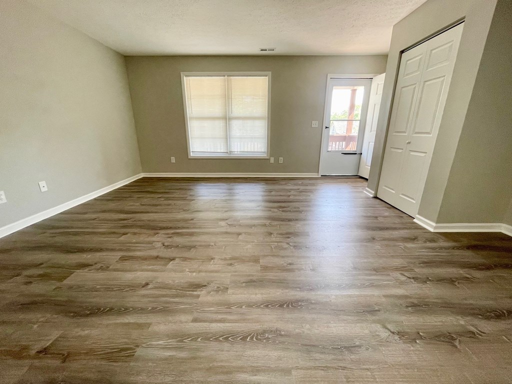 A room with wooden flooring and a door on the right.