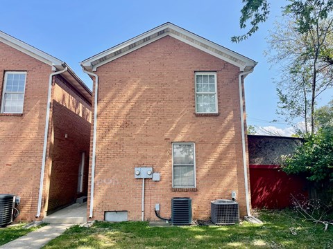 A red brick house with a white window and a door.