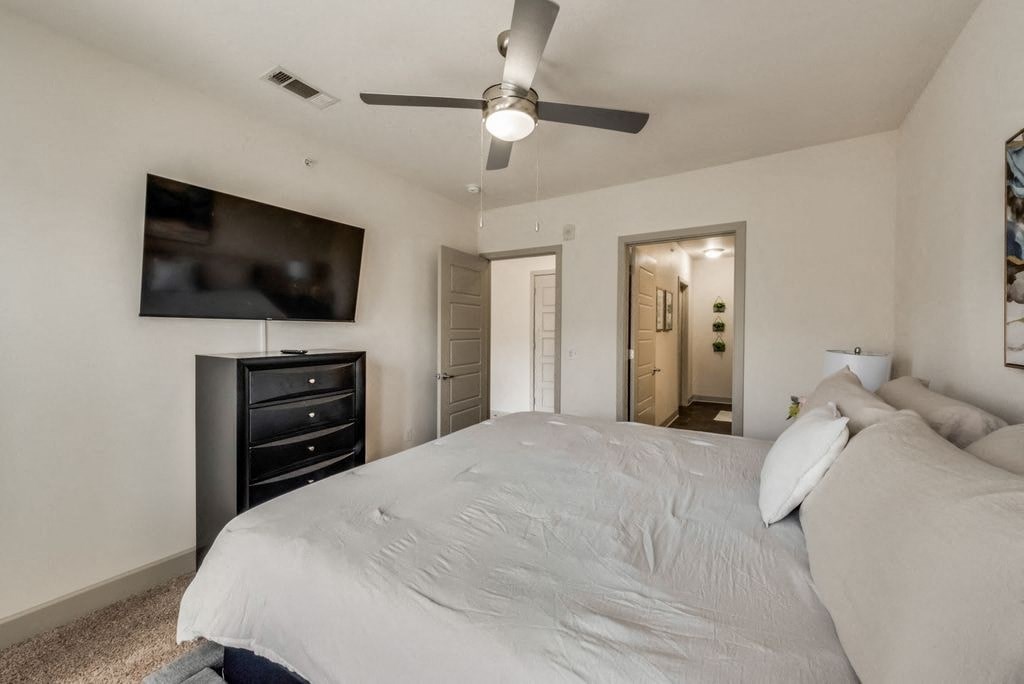 a white bedroom with a large bed and a ceiling fan