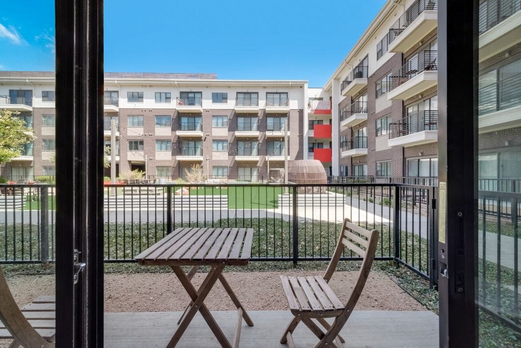 a balcony with a table and chairs in front of an apartment building