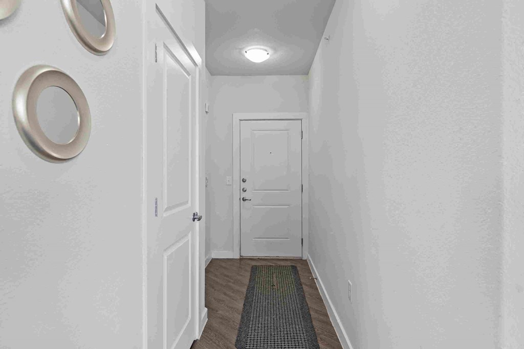 a white hallway with a white door and a door way to a closet