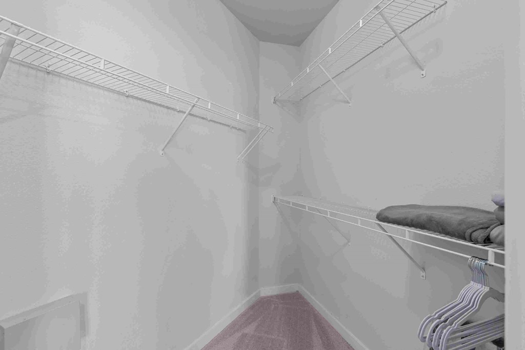 a white closet with shelves and racks in a room with a red floor