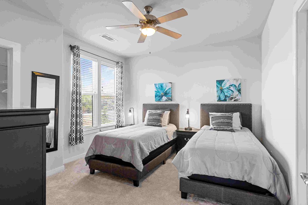 two beds in a white bedroom with a ceiling fan