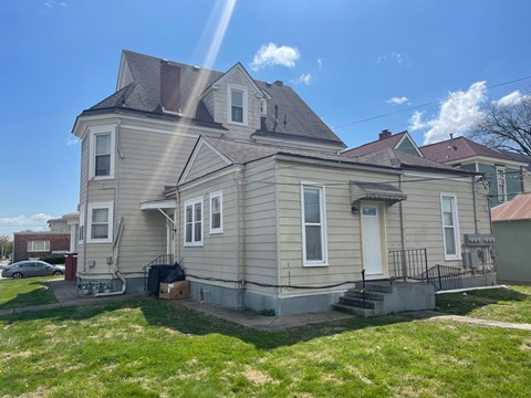 a tan house with a gray roof and a yard
