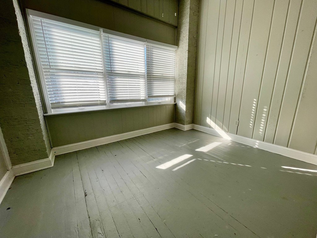 an empty room with windows and wood floors