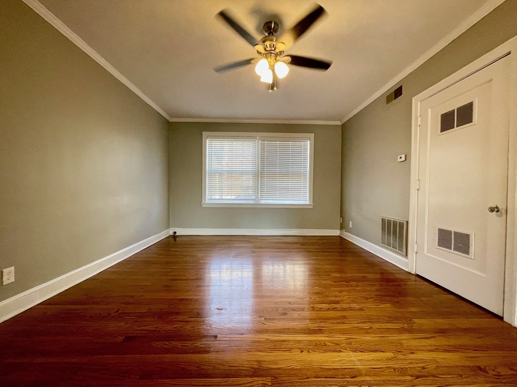 an empty living room with wooden floors and a ceiling fan