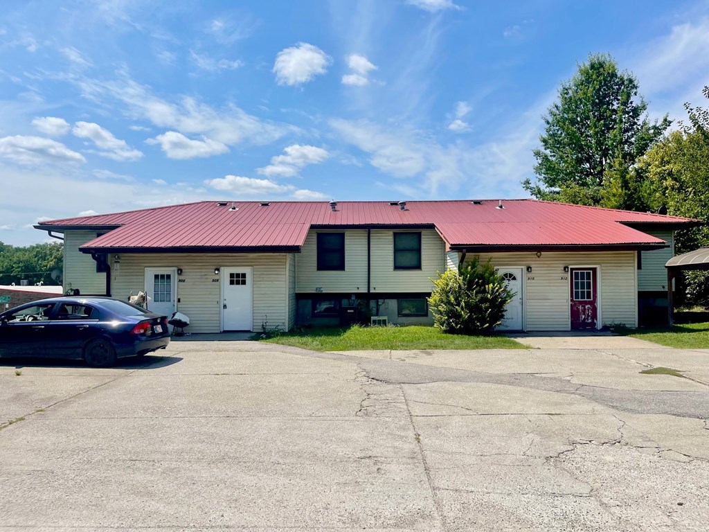 A car is parked in front of a building with a red roof.