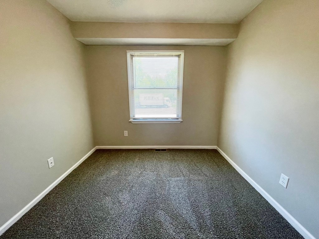 A room with a window and carpeted floor.