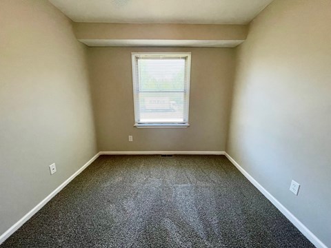 A room with a window and carpeted floor.