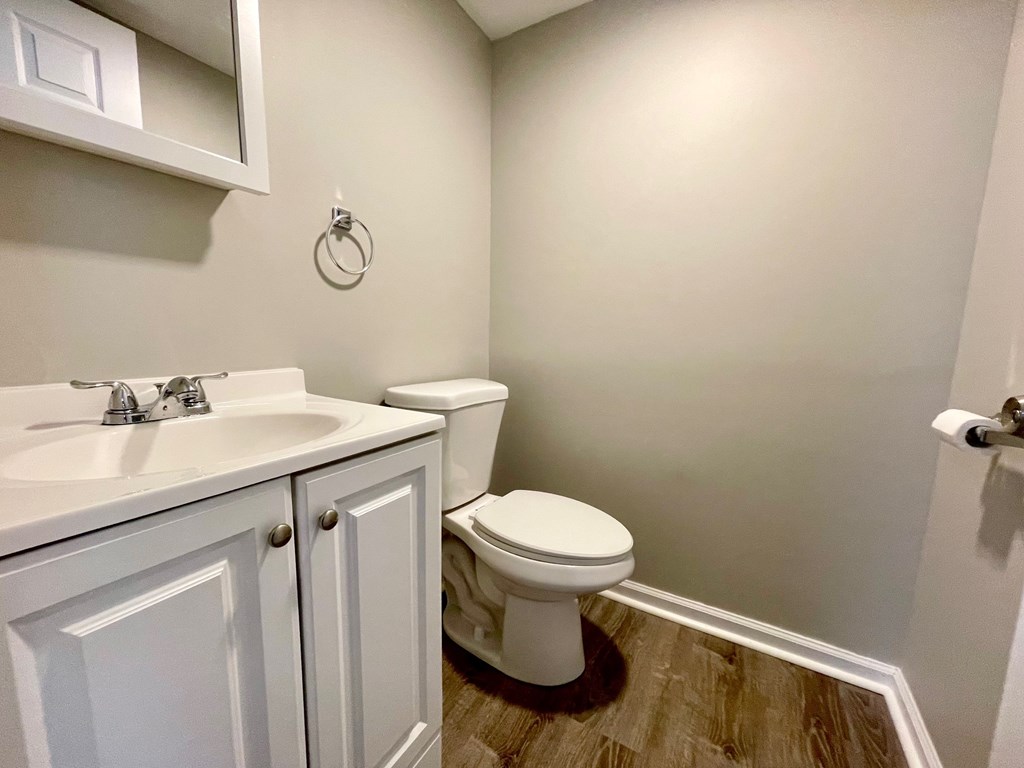 A white toilet sits in a bathroom next to a sink.