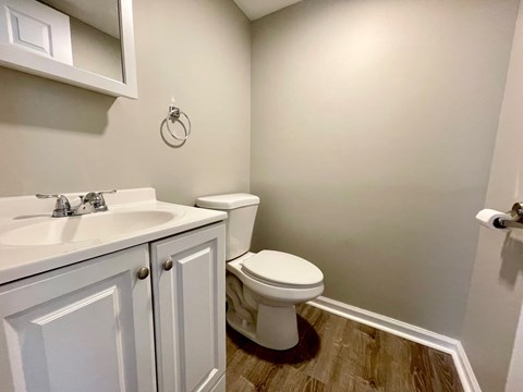 A white toilet sits in a bathroom next to a sink.