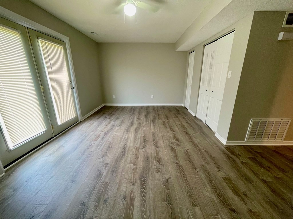 A room with wooden flooring and a window with blinds.