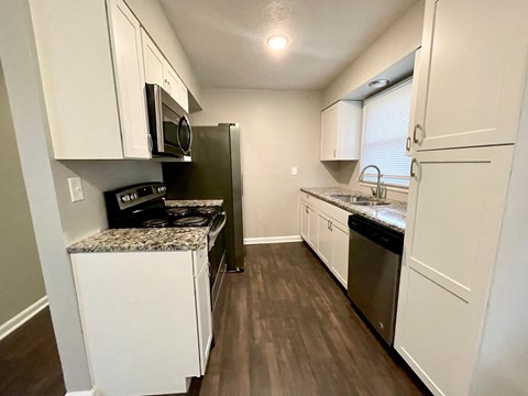 an empty kitchen with white cabinets and stainless steel appliances