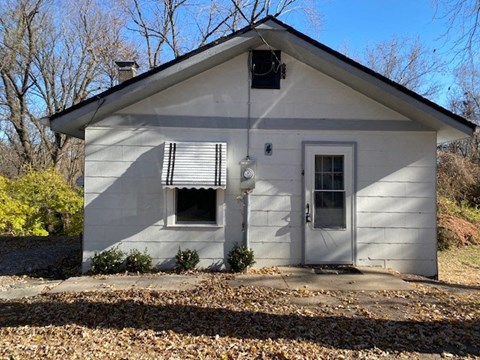A small white house with a broken window and a door.