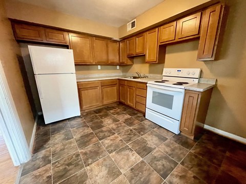A kitchen with a white fridge and stove top oven.