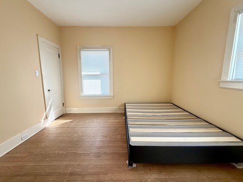 A bedroom with a bed, window, and door.