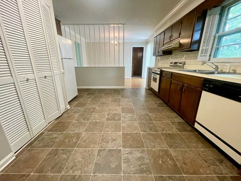 A kitchen with brown tiled floors and white cabinets.