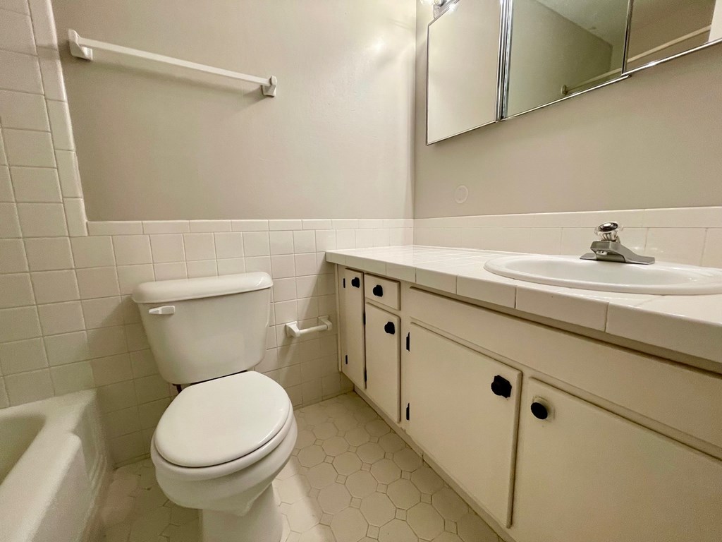 A white toilet with a white sink and a white bathtub in a bathroom.
