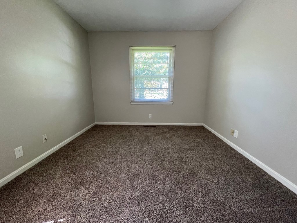 A room with a window and carpeted floor.