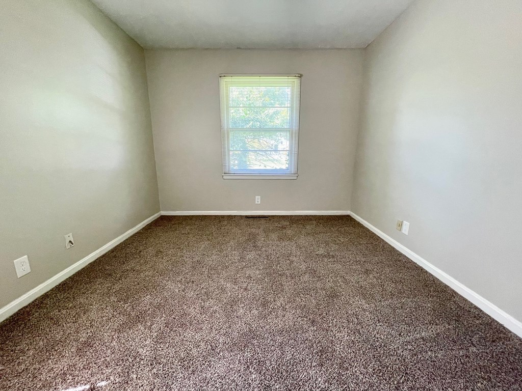 A room with a carpeted floor and a window.