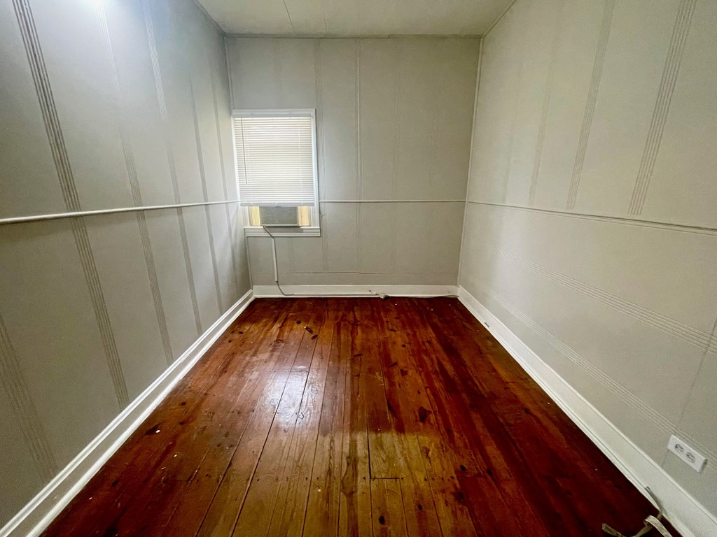 a room with wooden floors and white walls and a window