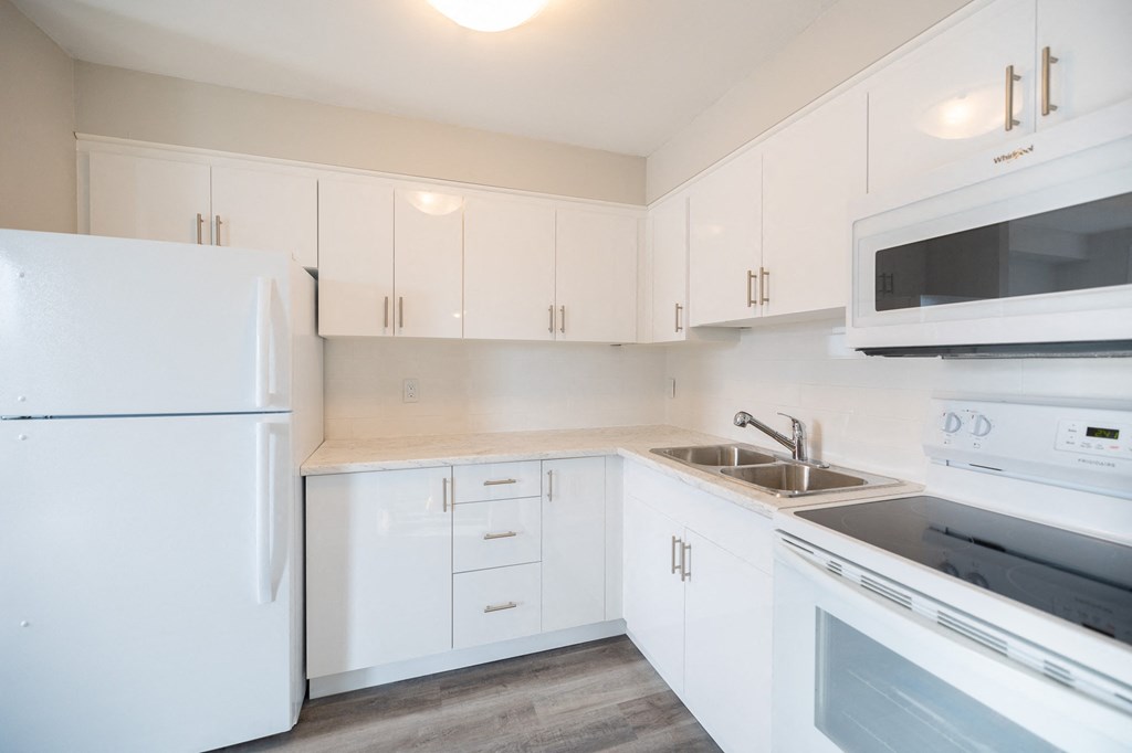 a kitchen with white cabinets and a sink and a refrigerator