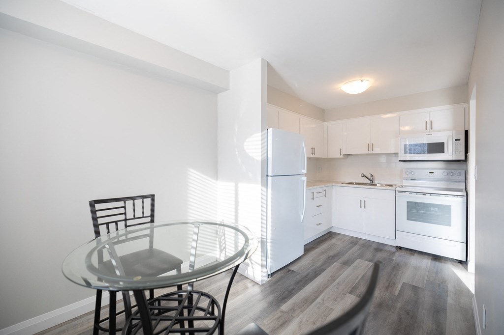 a kitchen with white appliances and a glass table and chairs