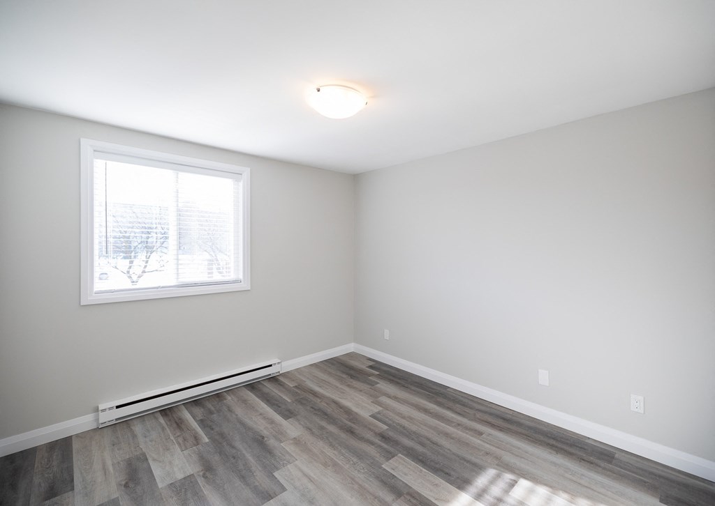 an empty room with wood flooring and a window
