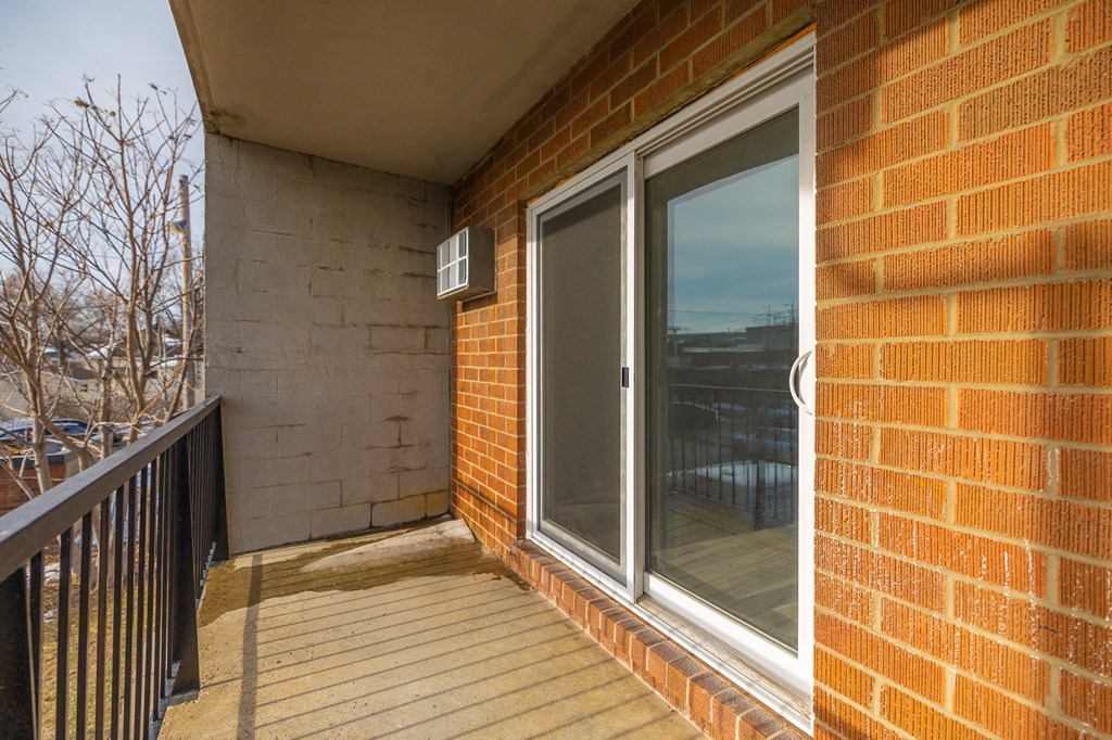 a balcony with a brick wall and a sliding glass door