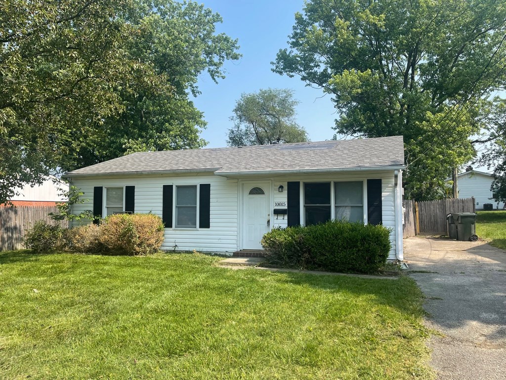 A white house with a black roof and a green lawn.