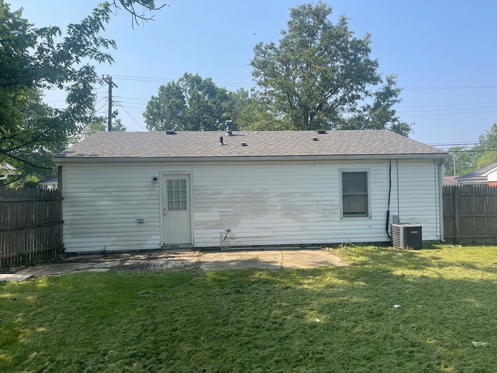 A small white house with a grey roof and a green lawn in front.