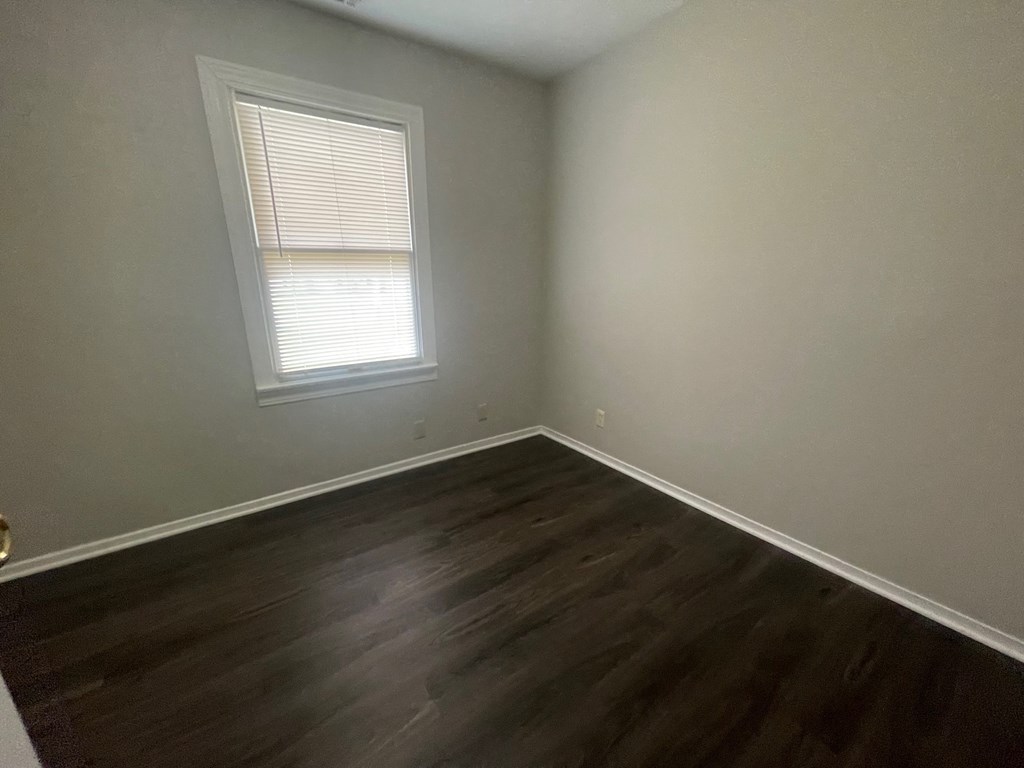 A room with a window and wooden flooring.